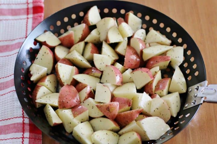 seasoned and diced red potatoes shown in a round black grill pan.