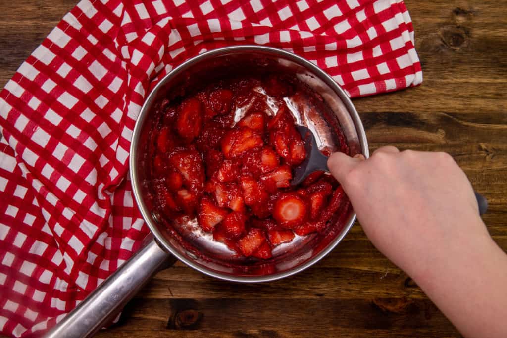 stirring in fresh sliced strawberries to strawberry cornstarch mixture in a medium saucepan on an electric countertop burner.