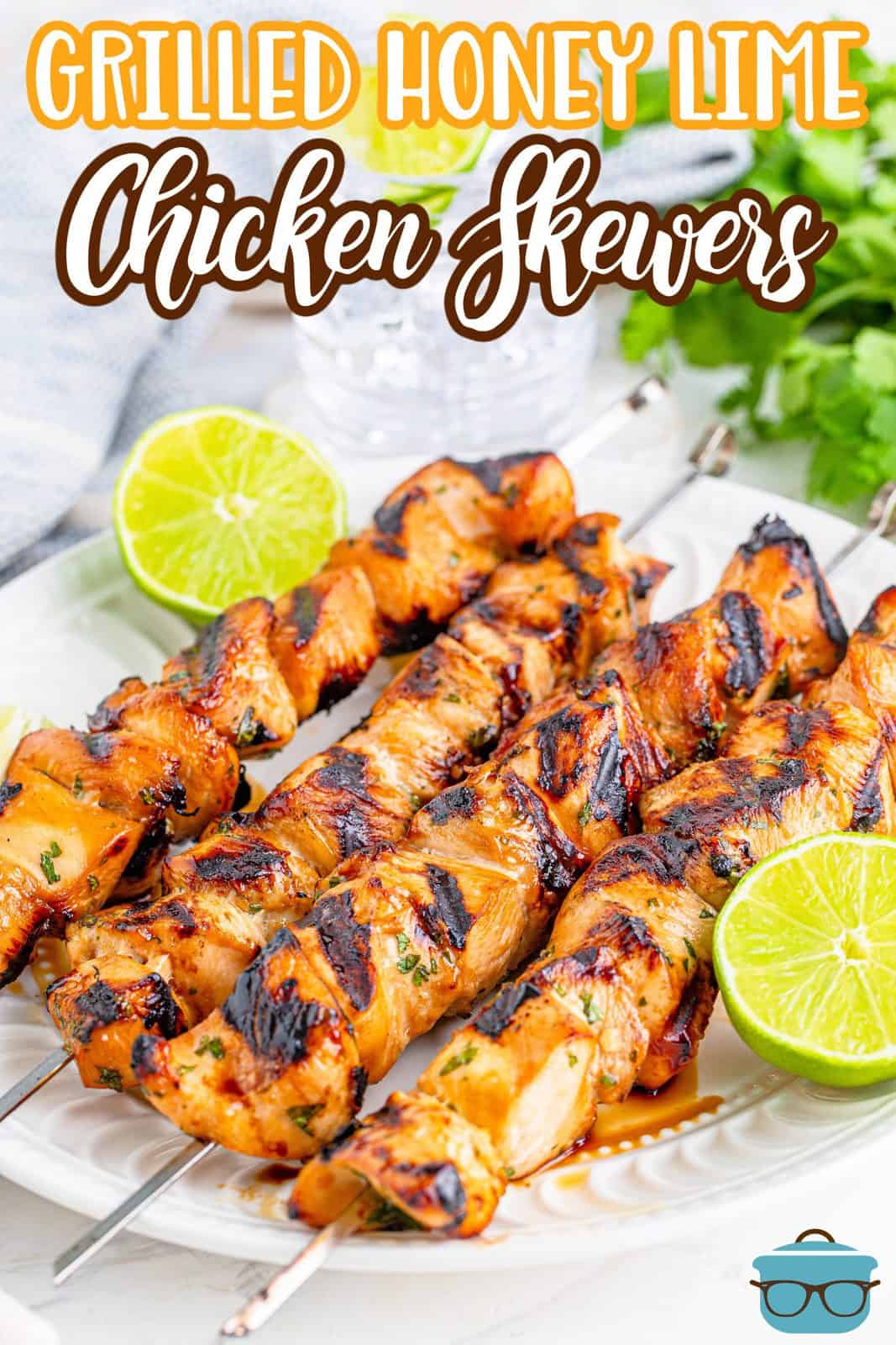Grilled Honey Lime Chicken Skewers shown on a white plate with sliced fresh limes. 