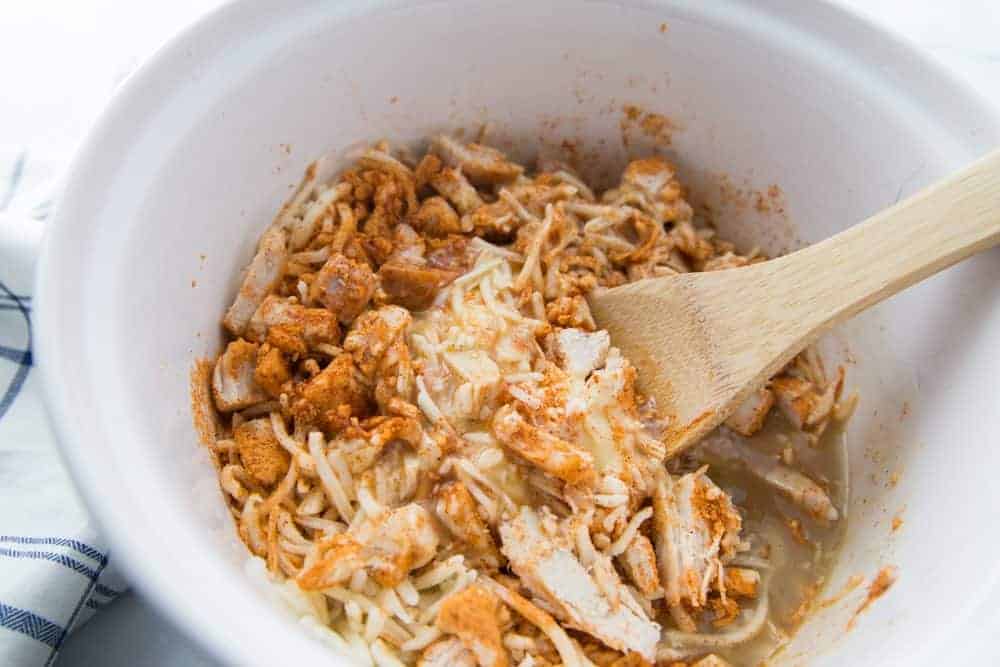 chopped rotisserie chicken, cream of chicken, green enchilada sauce and taco seasoning mixed in a bowl.