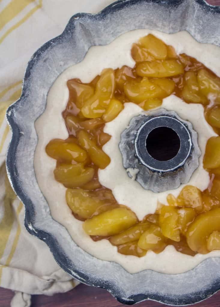 apple pie filling spread onto apple cinnamon muffin mix in a bundt pan.