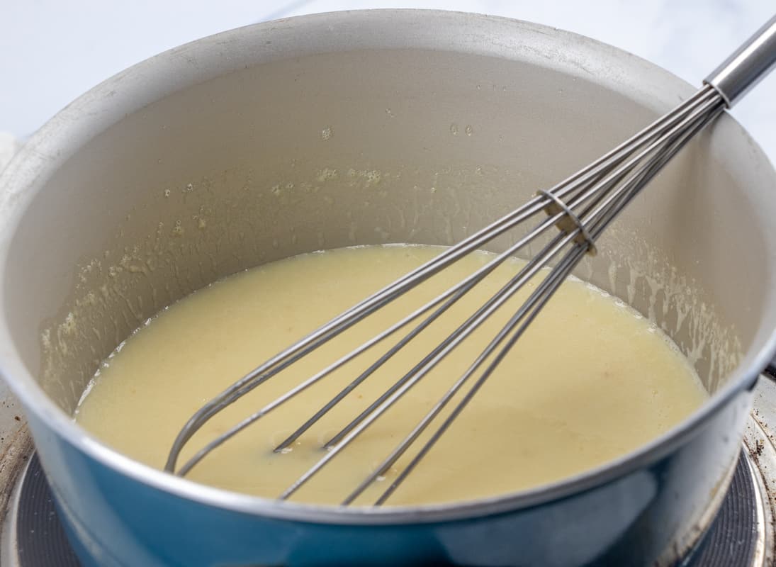 maple butter sauce for pancakes in a small pot with a whisk.