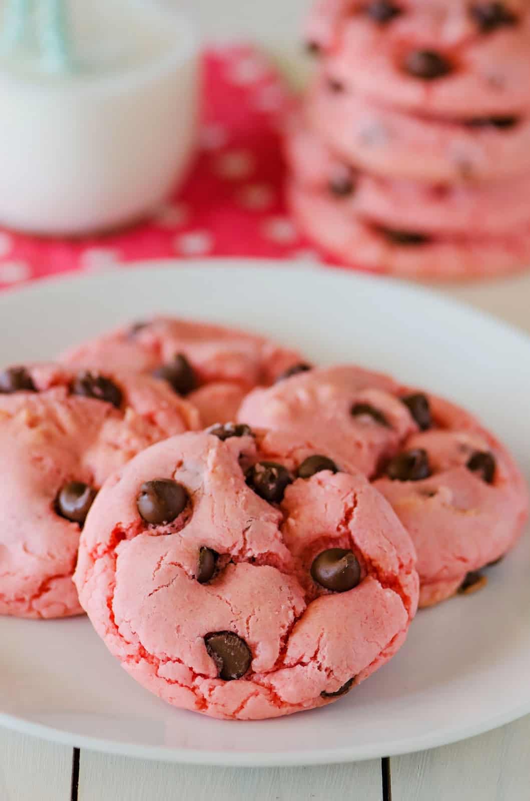 four strawberry chocolate chip cookies displayed on a round white plate.