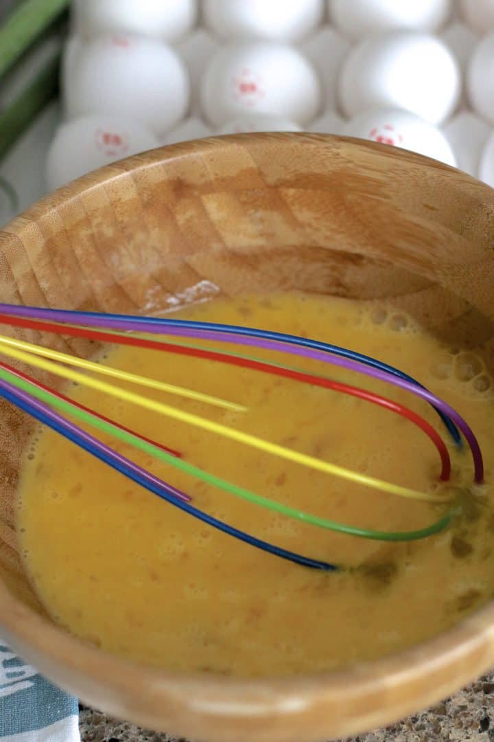 eggs being whisked in a wooden bowl.