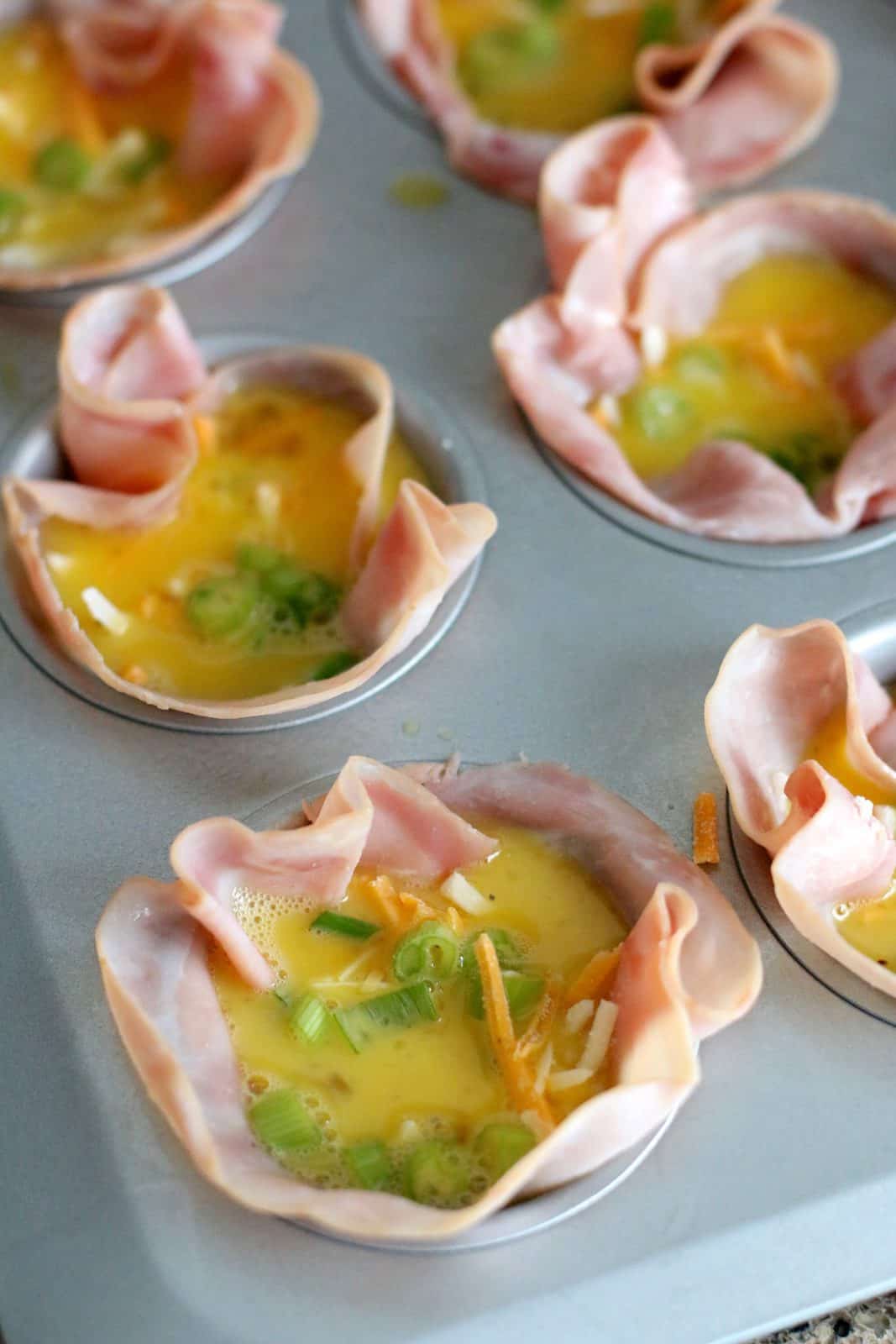 egg mixture added to ham slices in muffin tin.