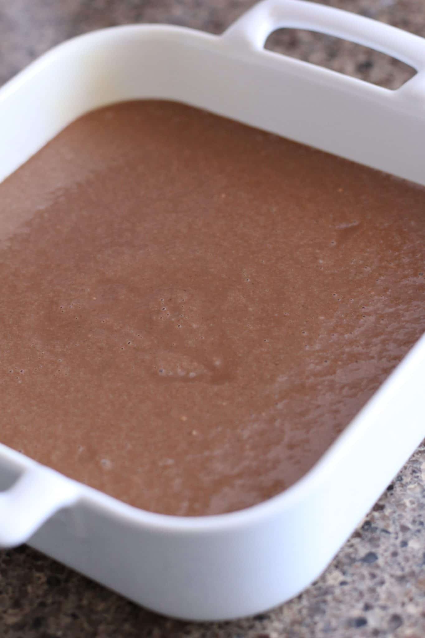 chocolate cake batter poured into a white square baking dish.