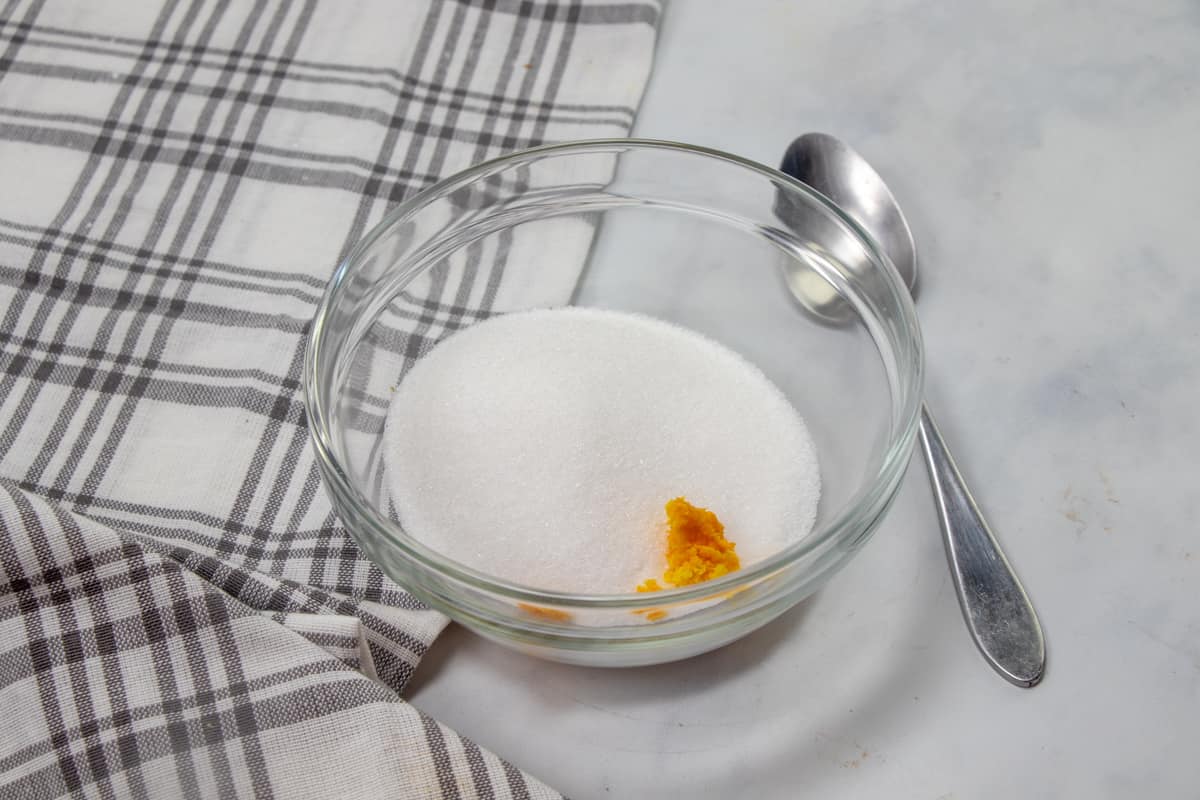 sugar and orange zest mixed together in a clear bowl.