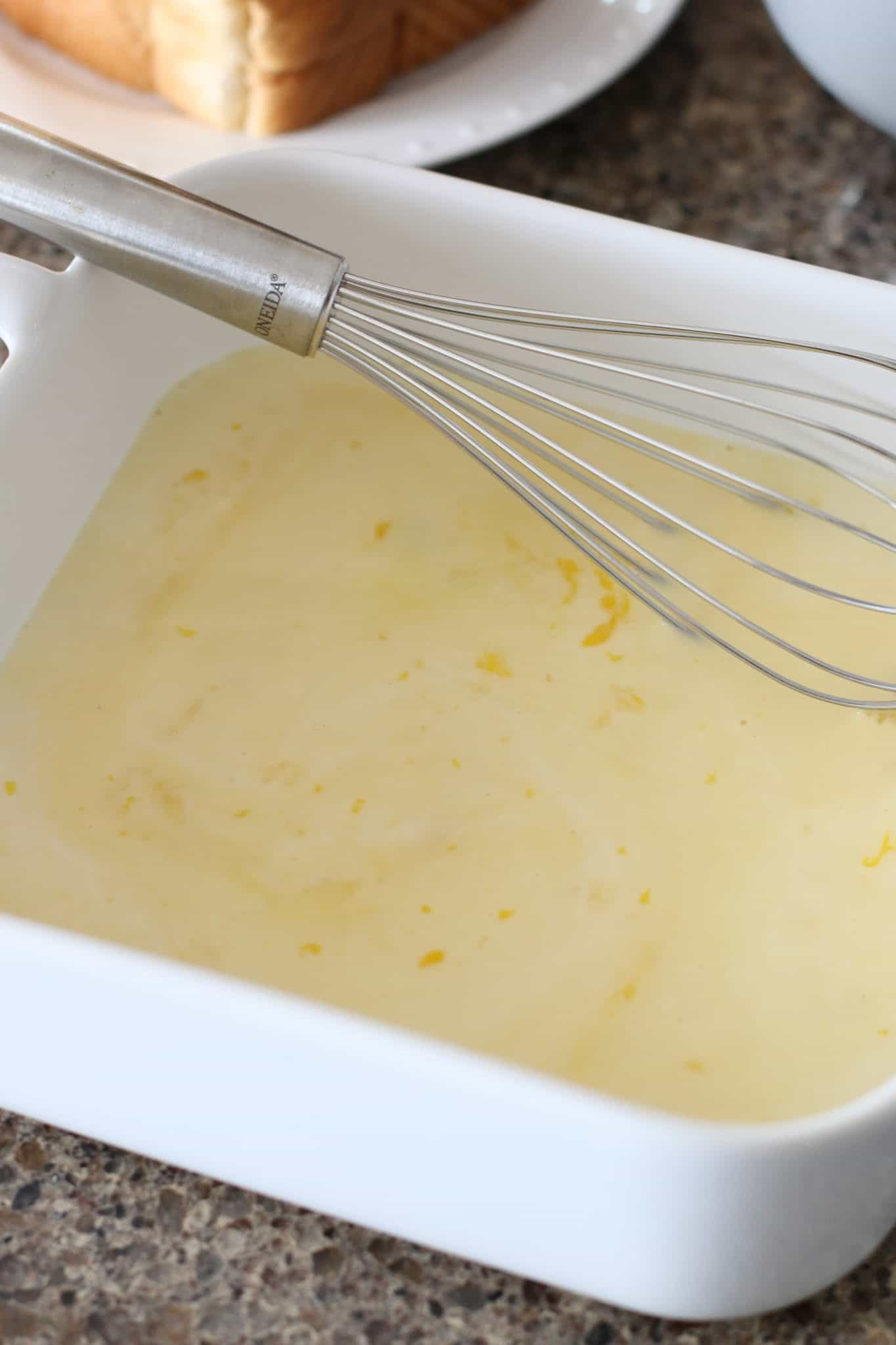 whisking eggs until combined in a white square baking dish.