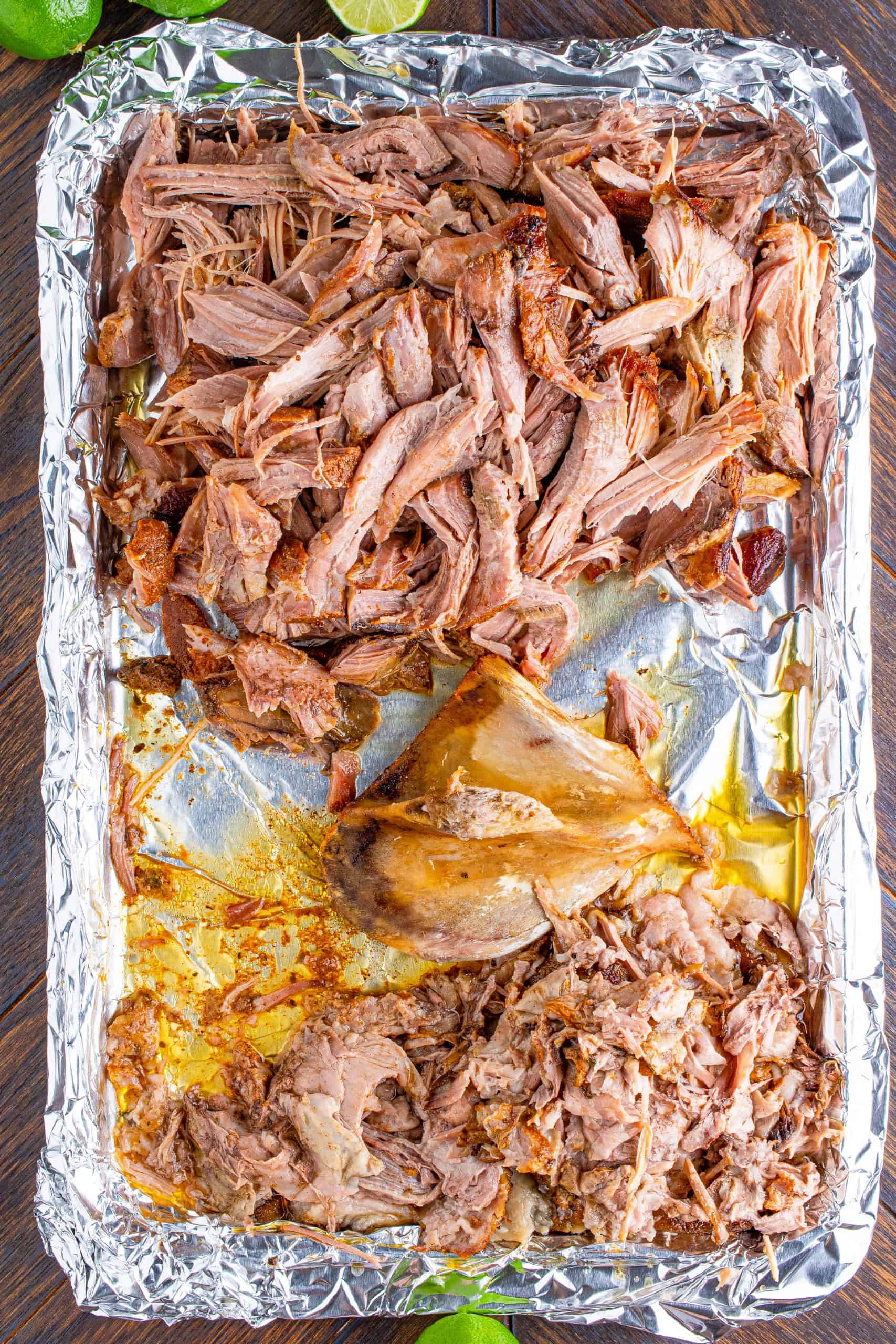 shredded pork shown on a tray lined with aluminum foil.