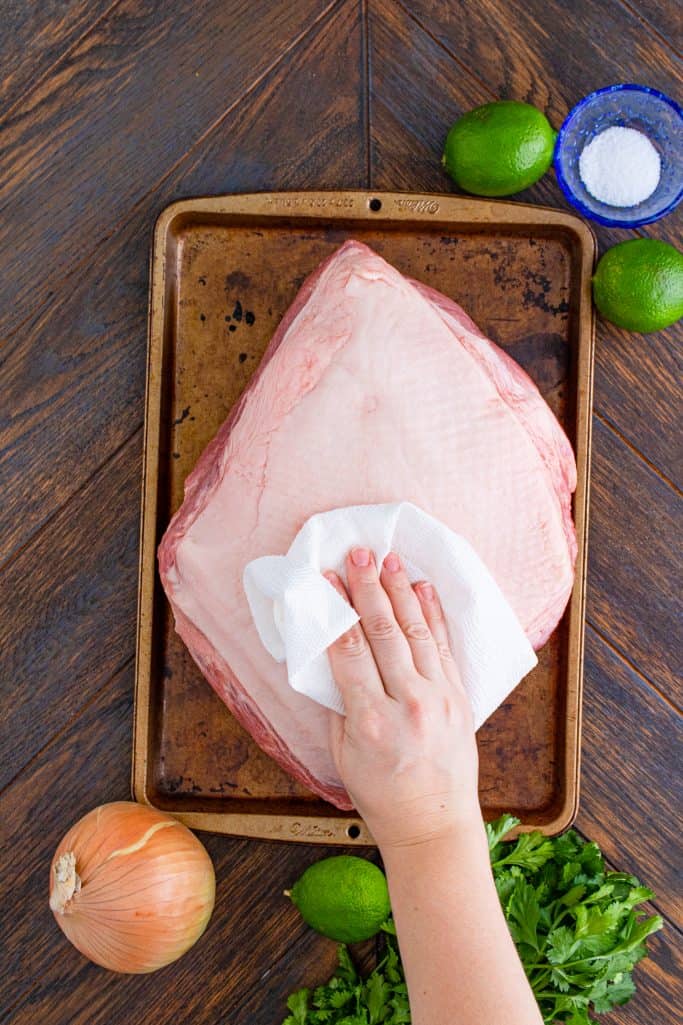 patting a pork roast with a paper towel to dry
