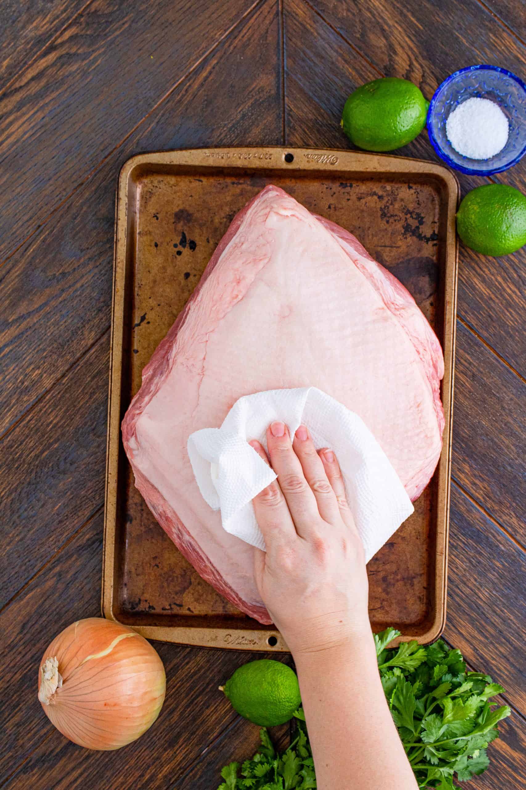 patting a pork roast with a paper towel to dry.
