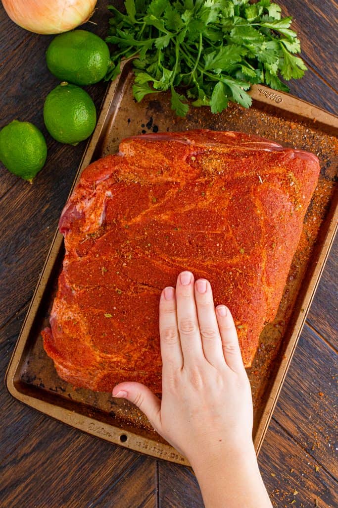 rubbing seasoning and spices into a pork roast on a baking tray