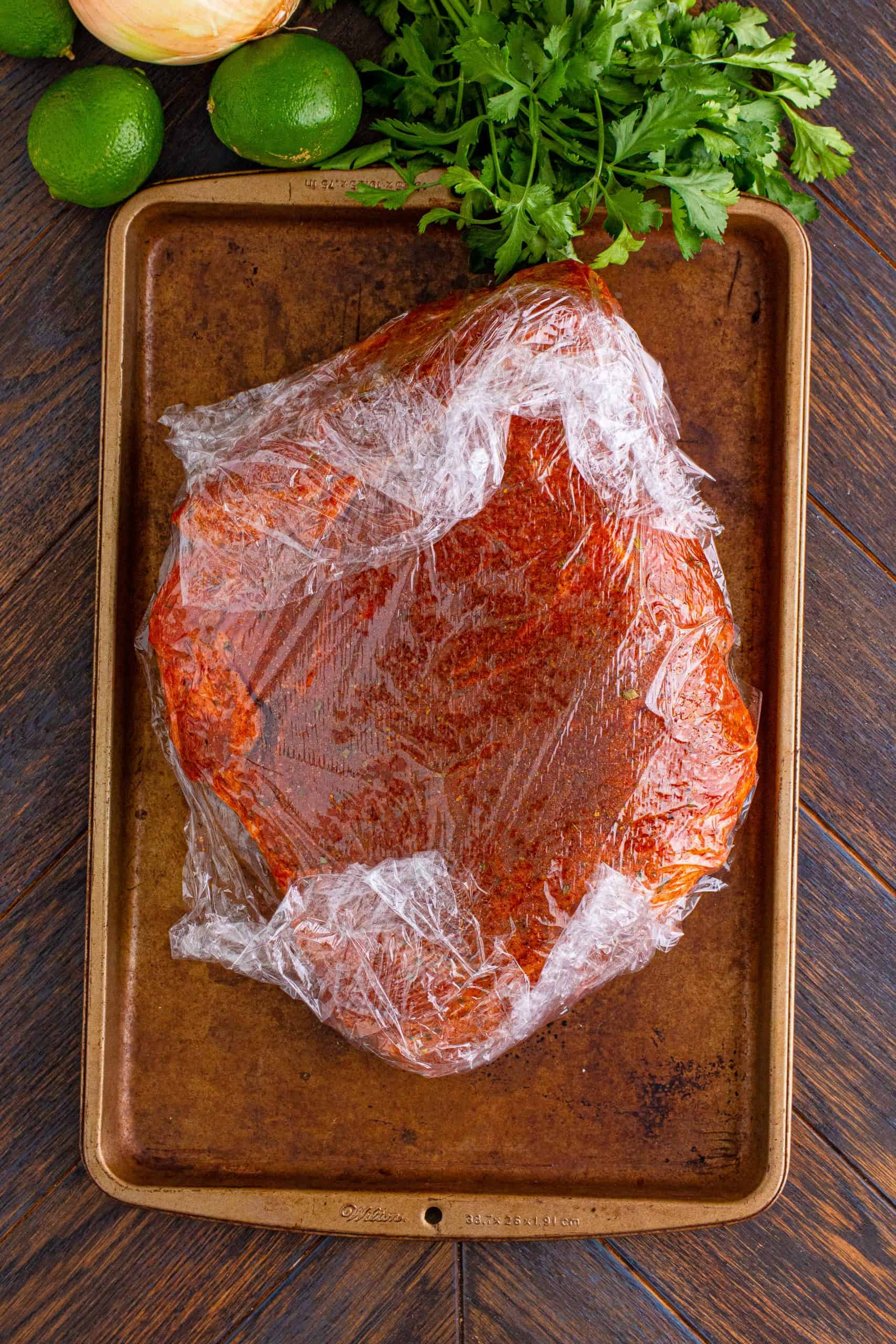 seasoned pork roast wrapped in plastic wrap.