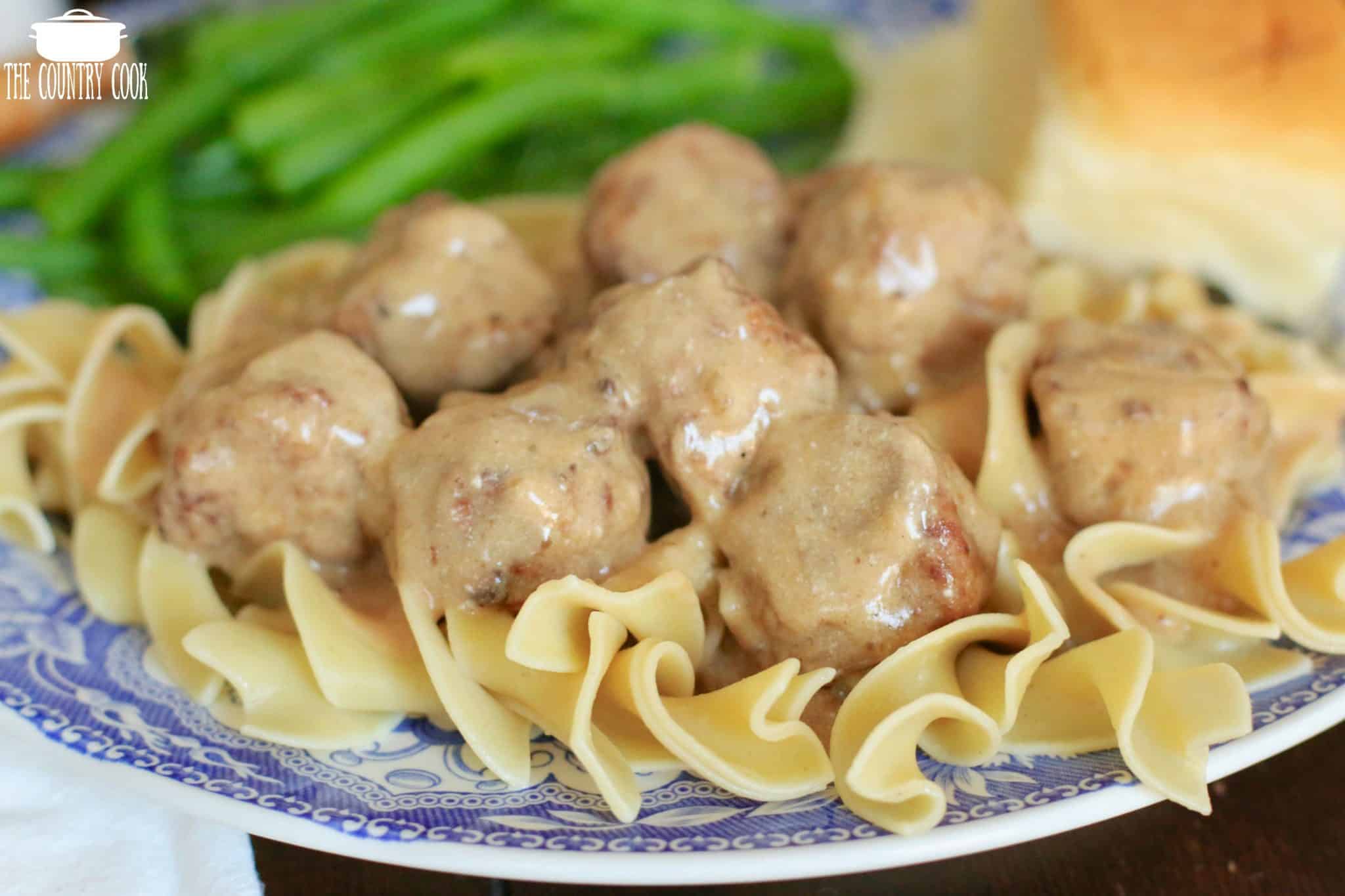 Slow Cooker Meatballs and Gravy on top of egg noodles served with green beans and a roll