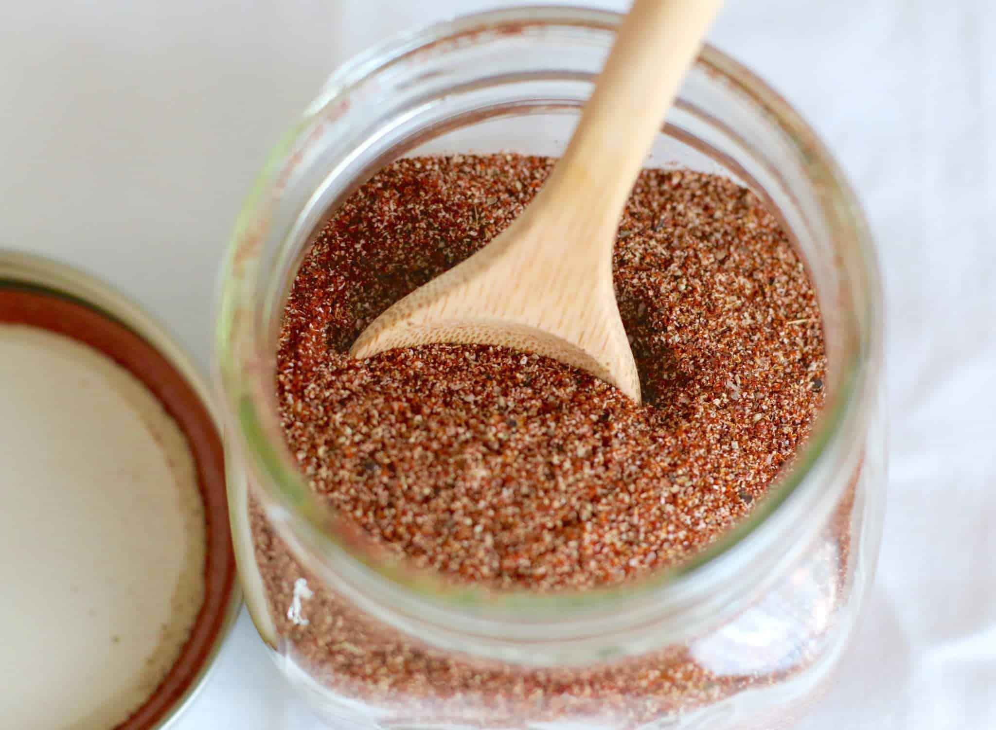 overhead photo of taco seasoning in a mason jar with a small wooden spoon stuck inside.