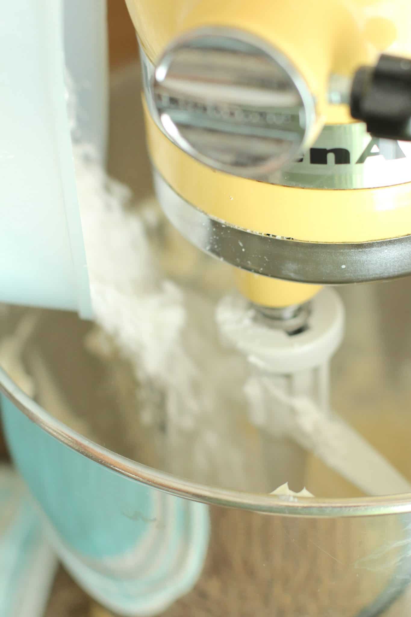 powdered sugar mixed together with butter and cream cheese in the bowl of a stand mixer
