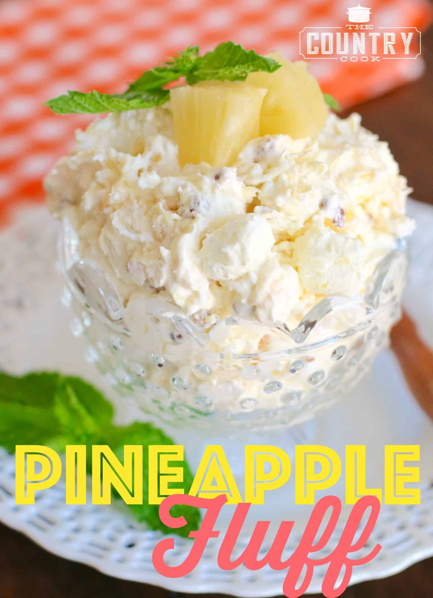 Pineapple Fluff shown in a clear, hobnail, dessert dish and topped with two chunks of pineapple.