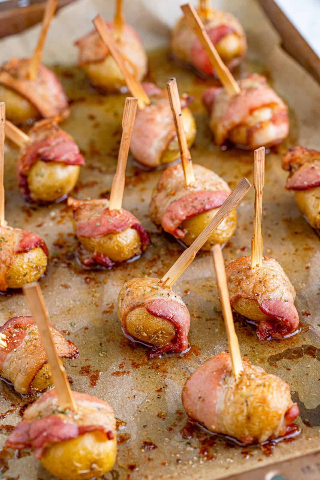 fully cooked bacon wrapped potatoes on a baking sheet.