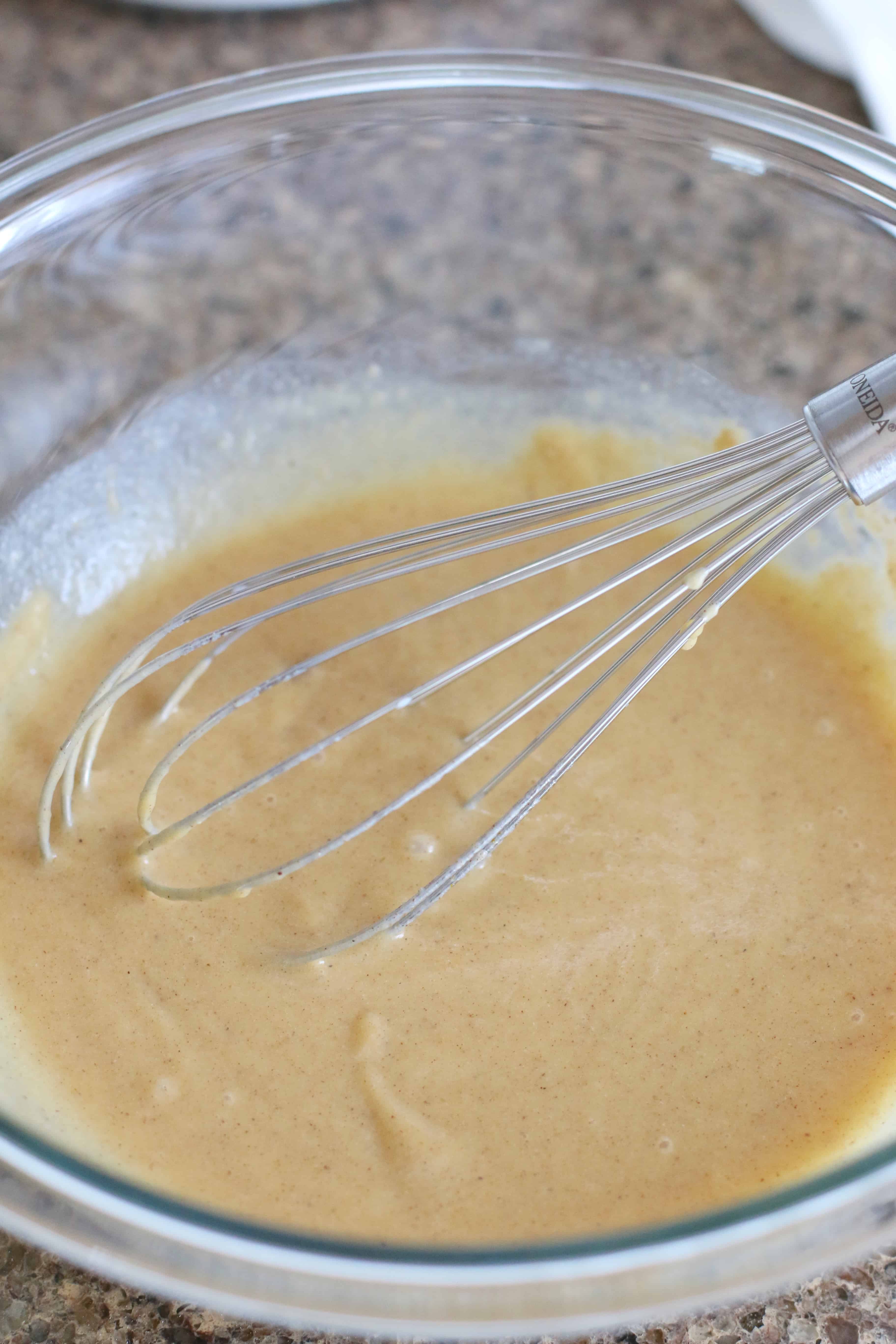 whisking together cold milk with instant vanilla pudding and pumpkin pie spice in a bowl.