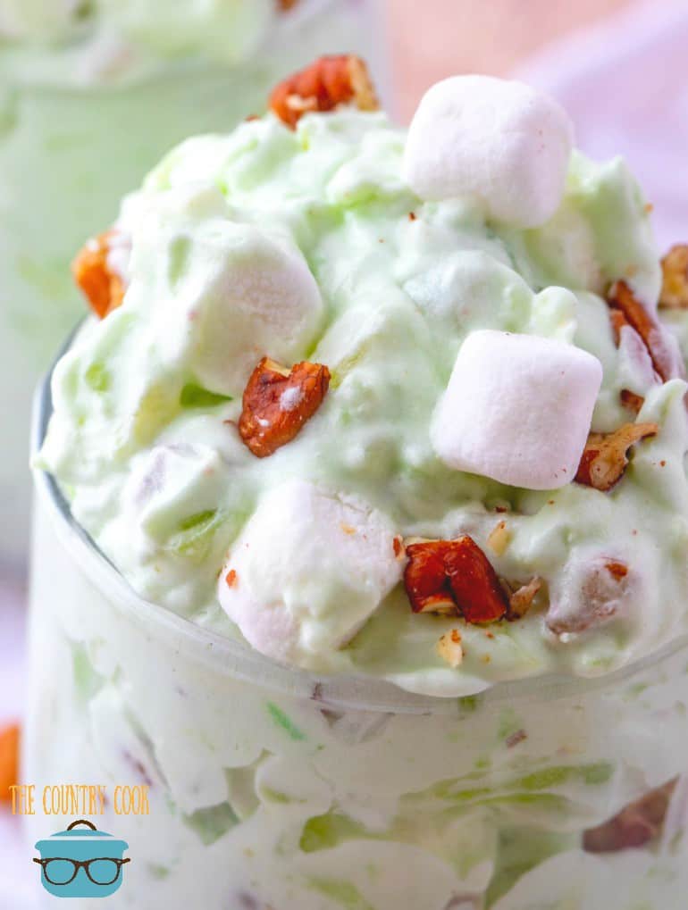 (close up) Pistachio fluff in a glass with marshmallows and pecans on top.