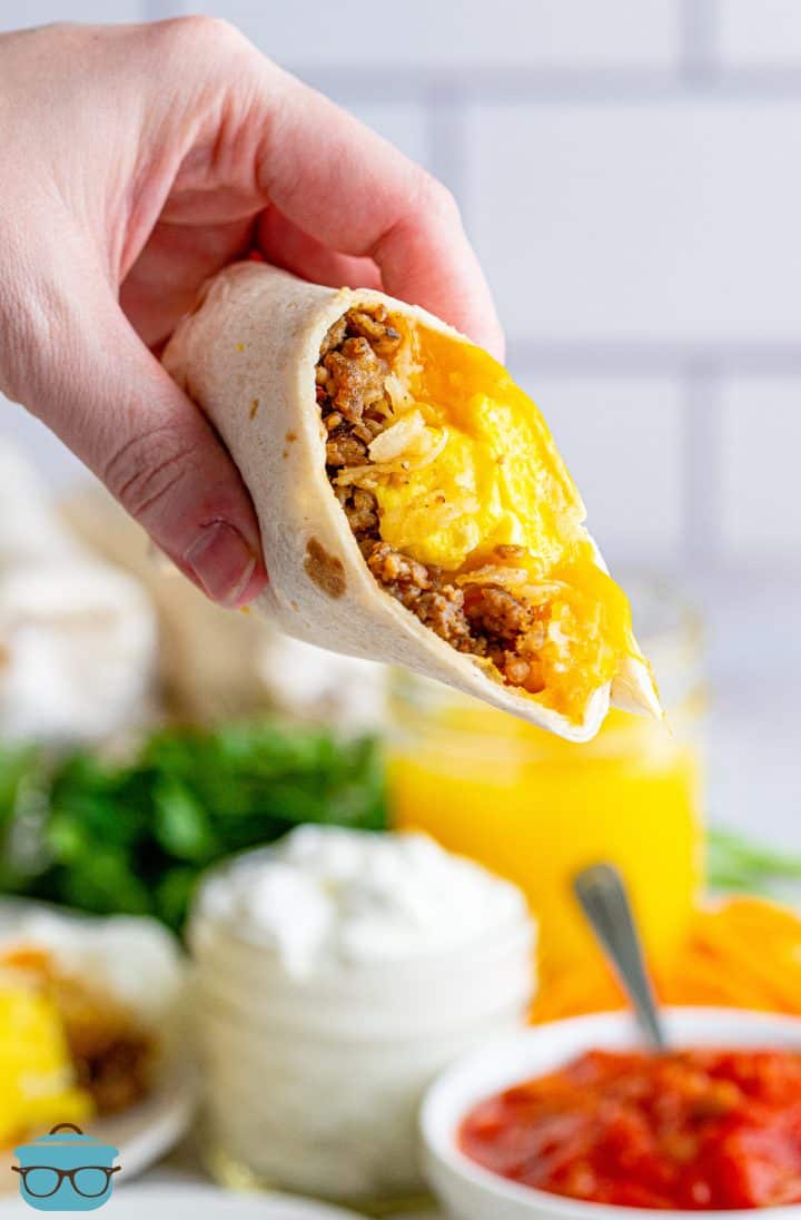 a hand holding up half of a breakfast burrito.