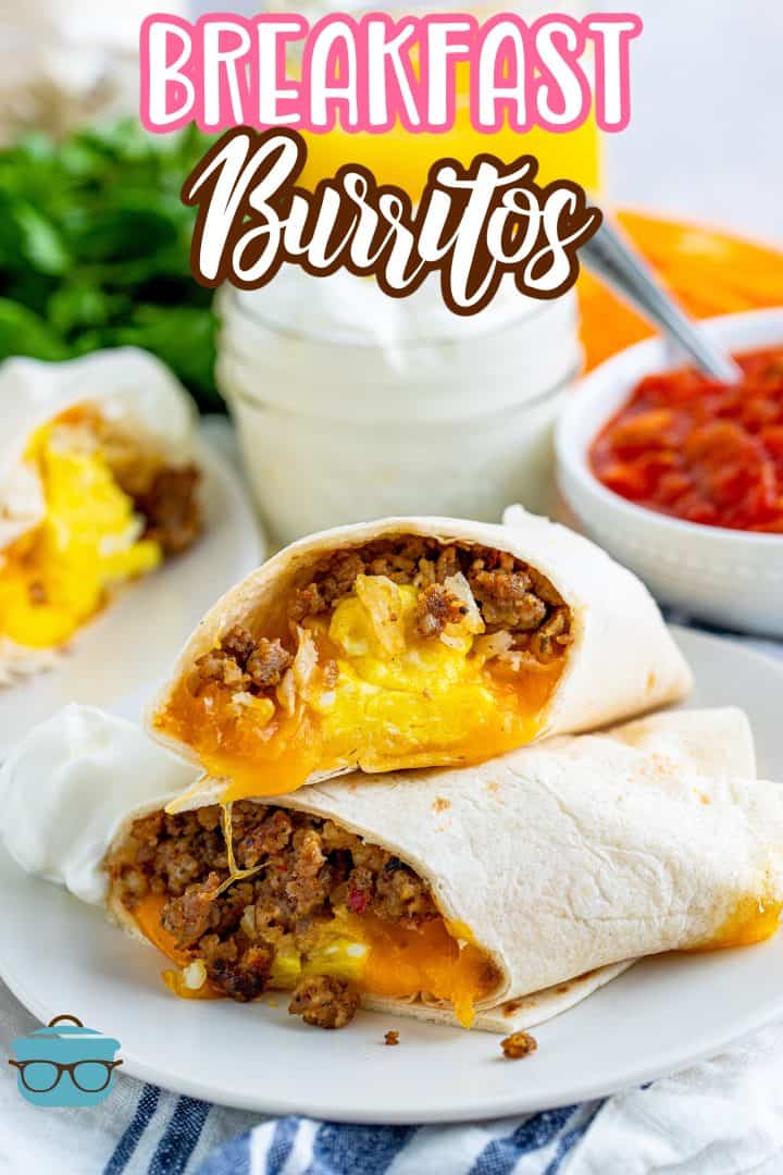 Breakfast Burritos shown sliced in half and stacked on top of each other on a white plate with a small bowl of salsa on the side.