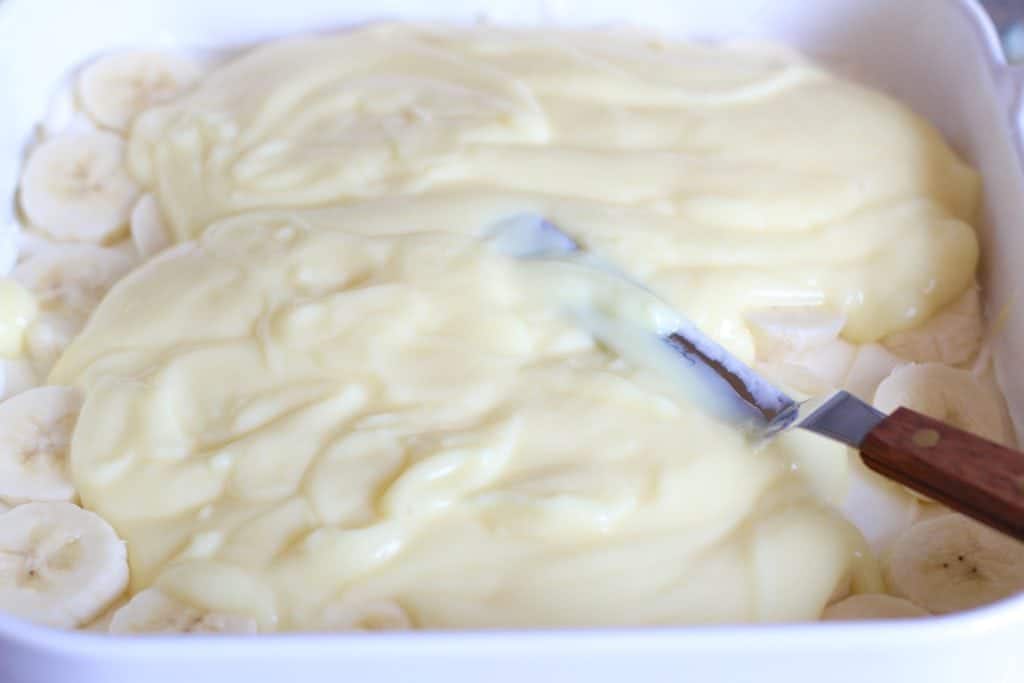 instant banana pudding mixture spread on top of sliced bananas