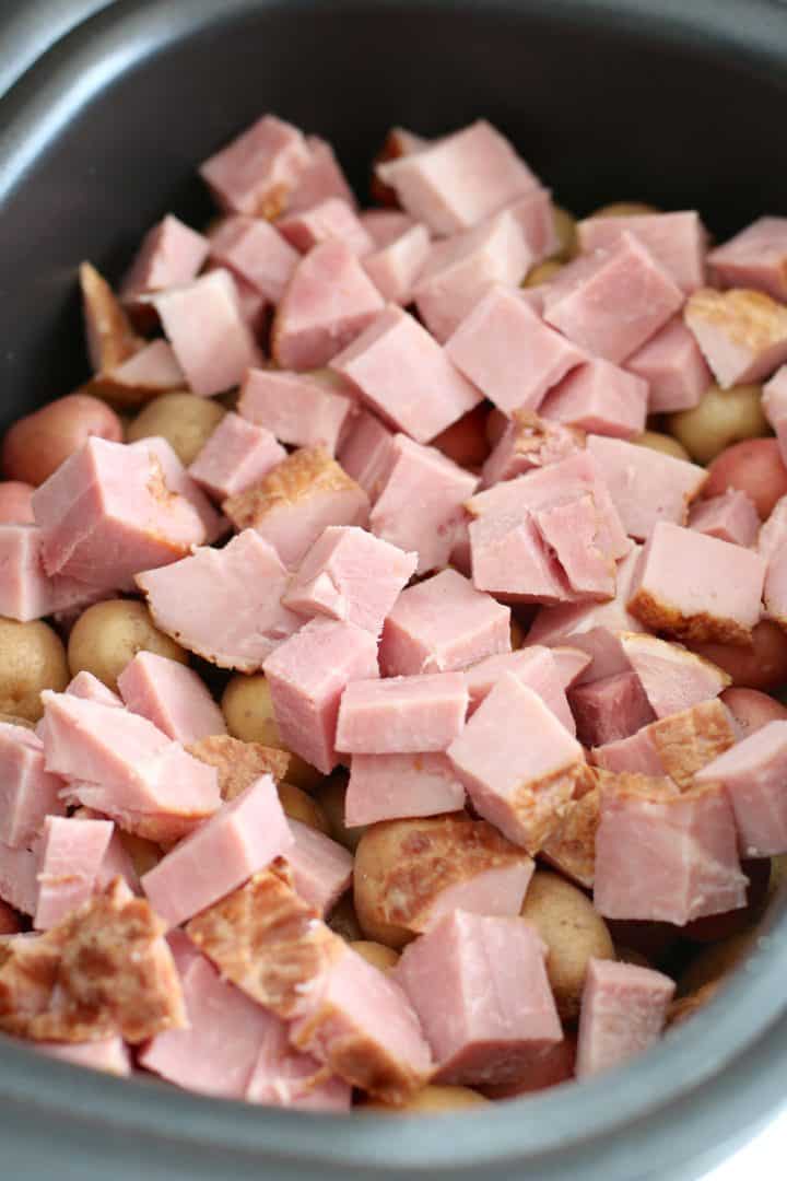 diced potatoes and diced ham in an oval slow cooker.