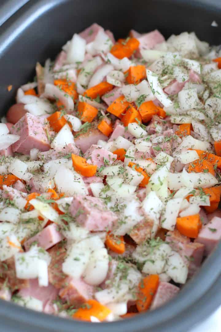 dried parsley and dried thyme sprinkled over ham and potatoes in a slow cooker.