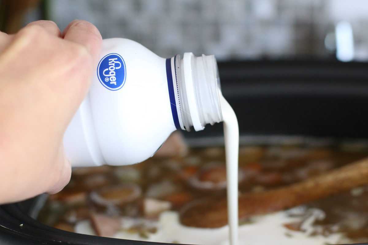 pouring heavy cream into a slow cooker.