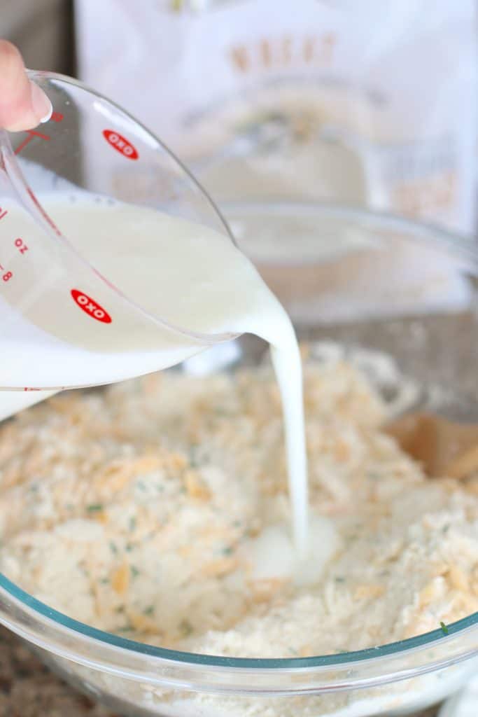 pouring milk into biscuit mix in a bowl.