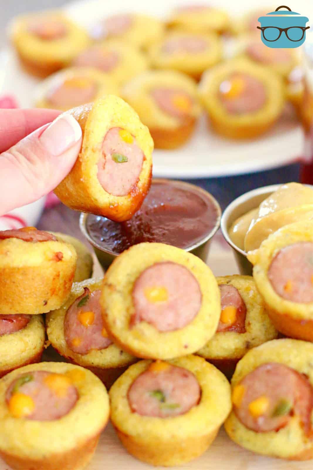 hand dipping cornbread sausage bite into ketchup.