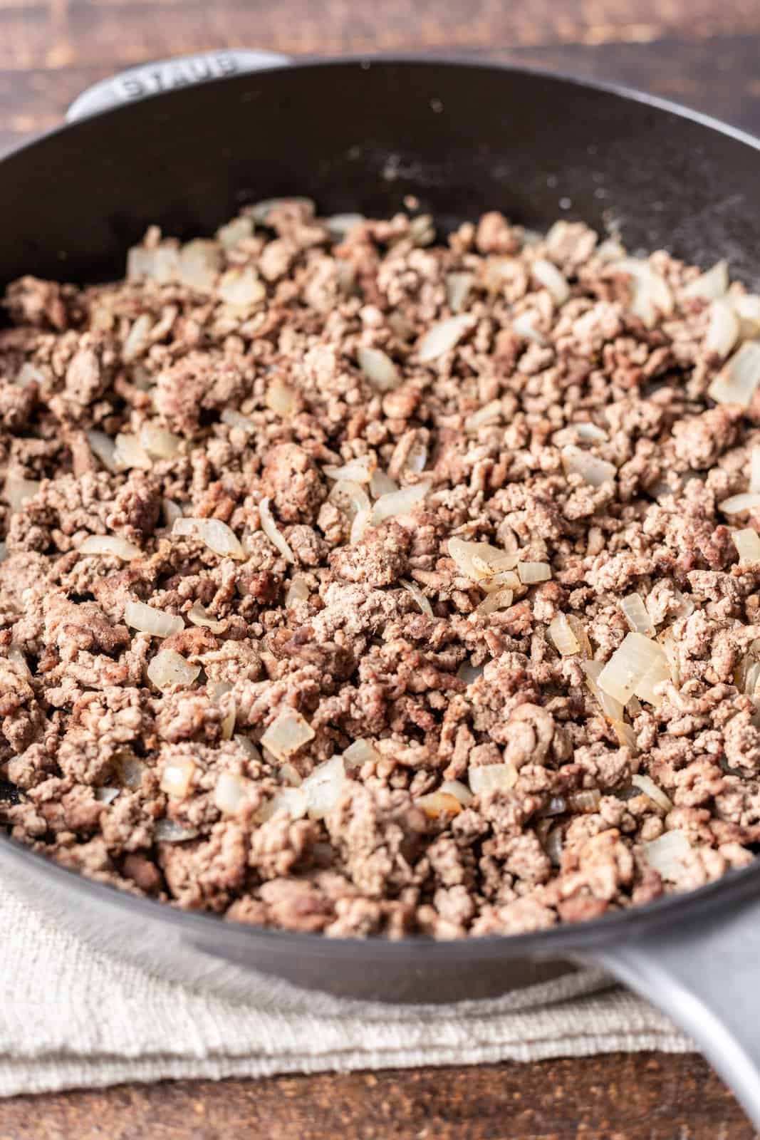 cooked and crumbled ground beef and diced onions in a skillet. 