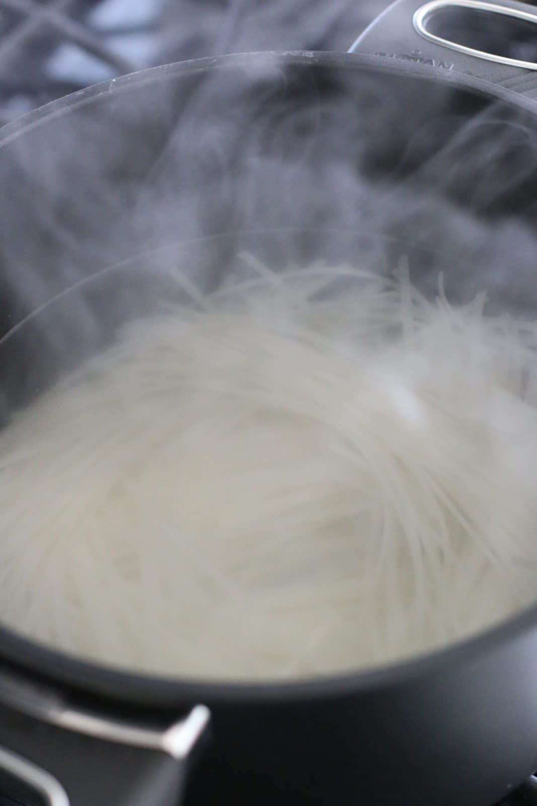 cooking rice noodles in a large pot of boiling water.