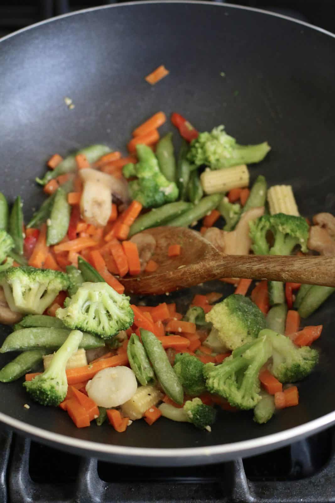 frozen vegetables added into a wok.