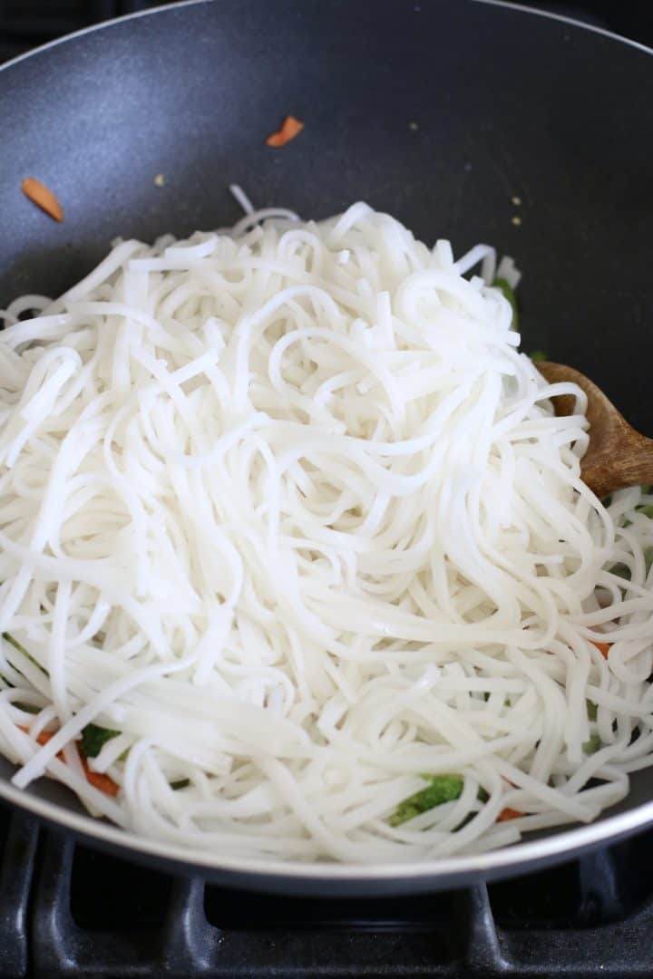 cooked rice noodles added to wok.