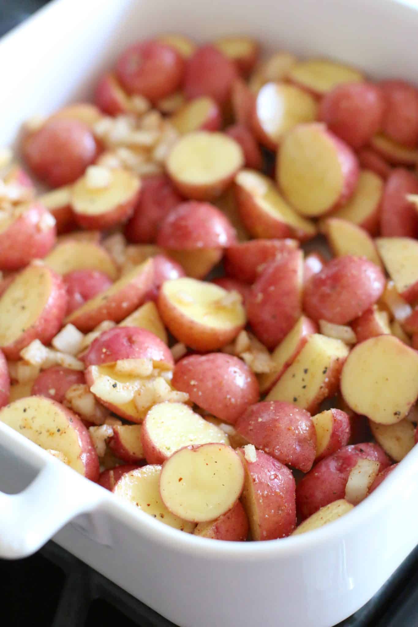 seasoned, sliced baby red Little Potatoes in a white Revol baking dish.