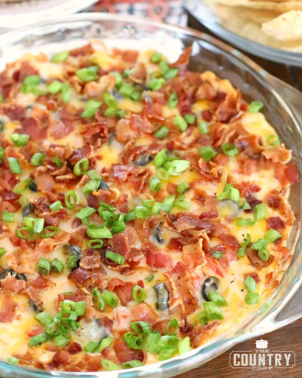 fully baked Warm Bacon Cheddar Dip in a clear pie baking dish.