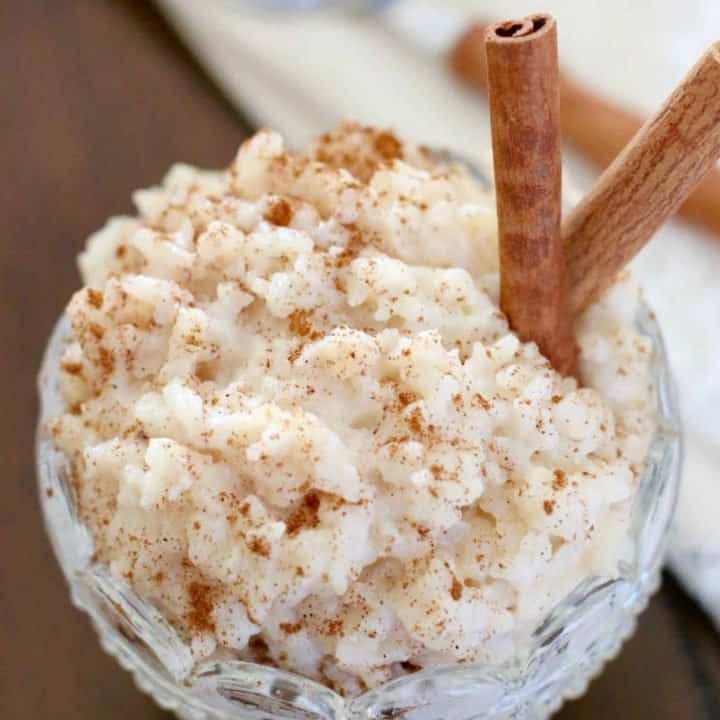 rice pudding in a decorative clear glass dessert bowl with two cinnamon sticks