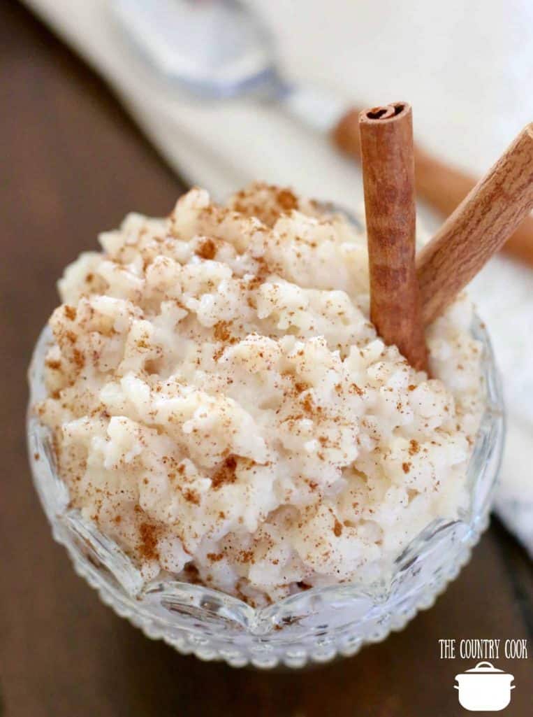 rice pudding in a decorative clear glass dessert bowl with two cinnamon sticks.