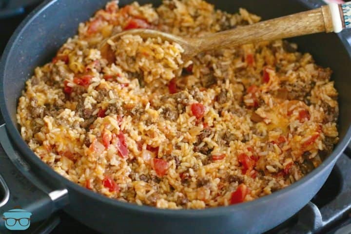 taco rice shown in a skillet with a wooden spoon.