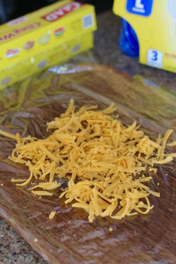 shredded cheddar cheese placed on top of plastic wrap.