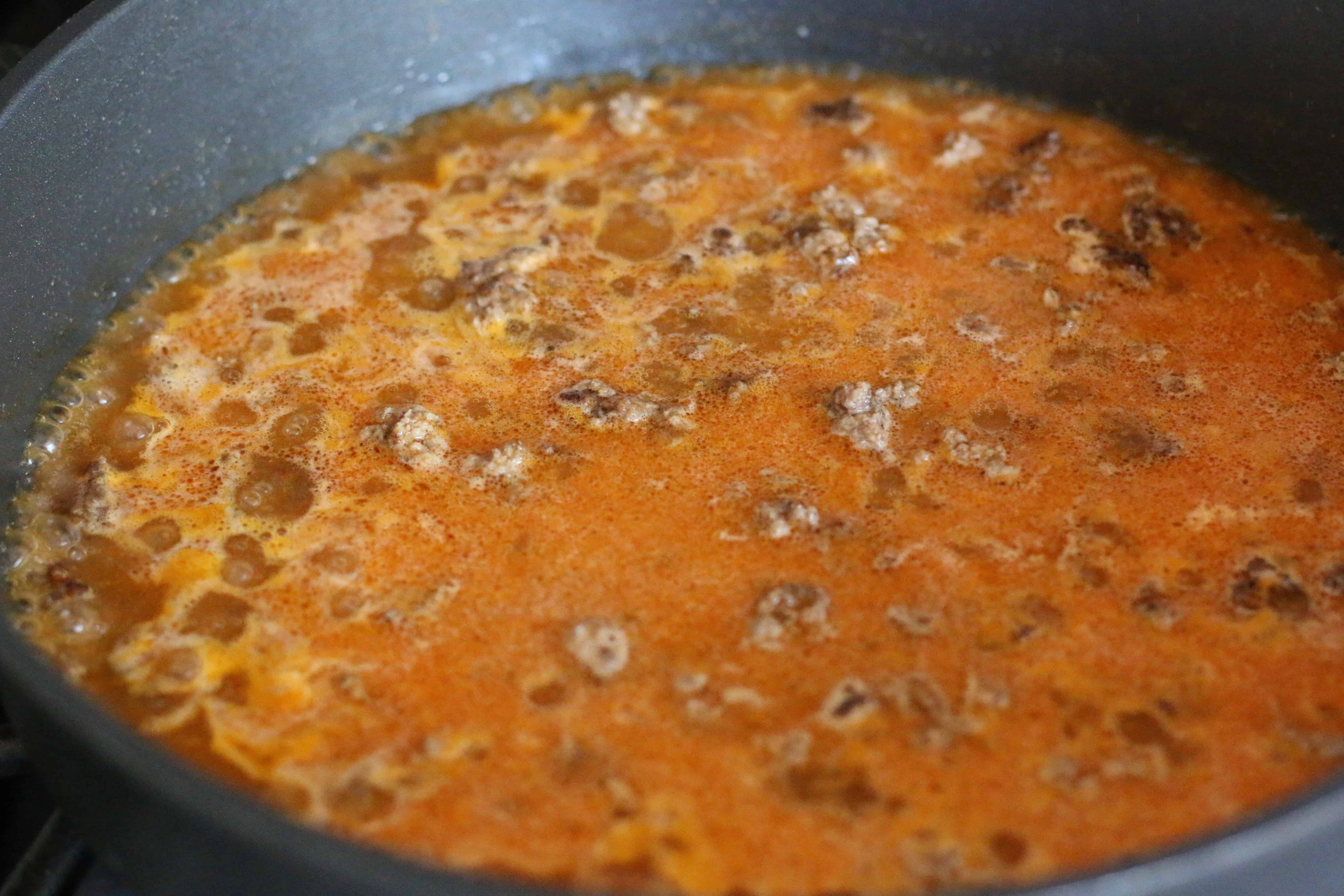 cooked ground beef, water and taco seasoning in a large skillet coming to a rolling boil.
