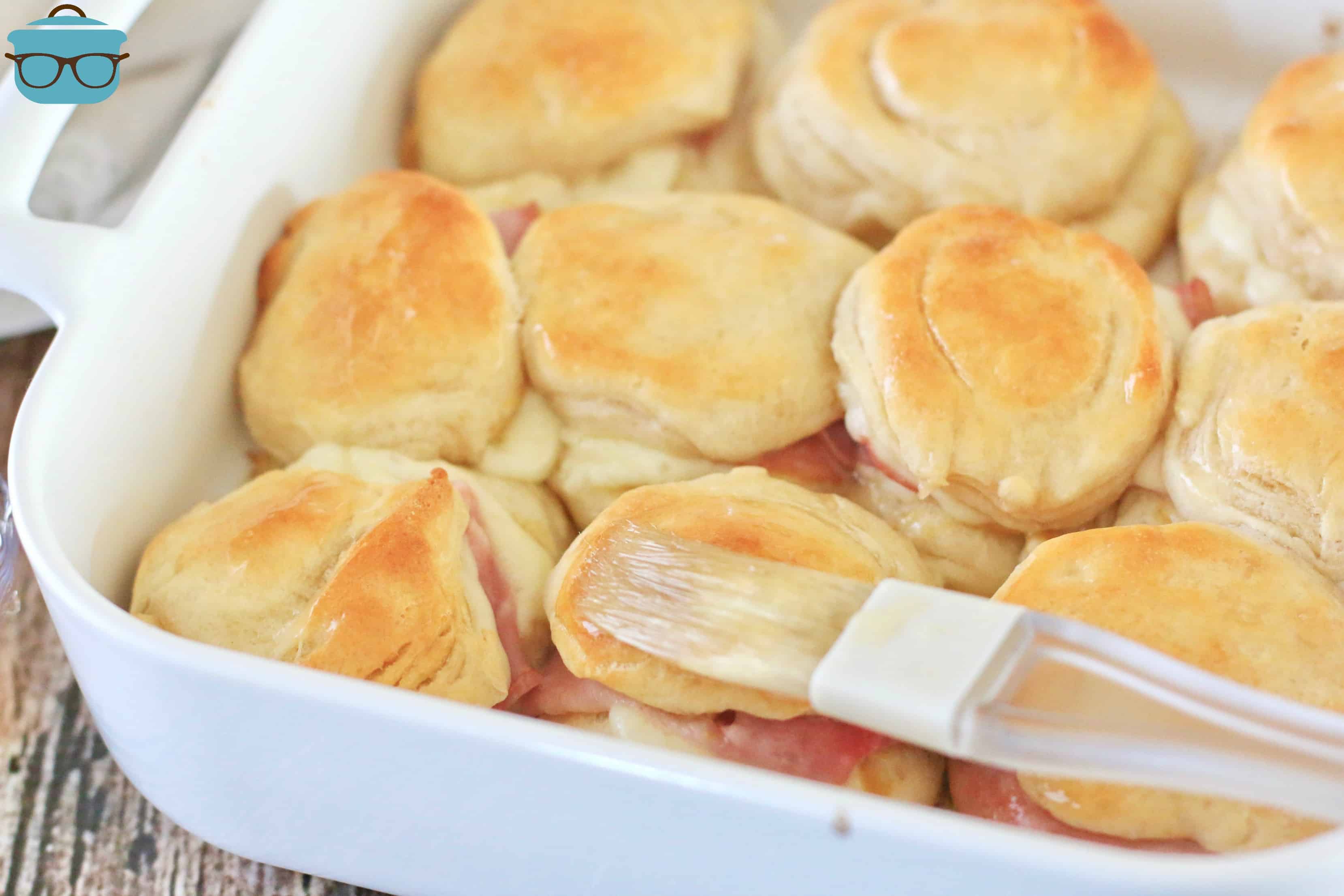 spreading warm honey on cooked ham biscuits.