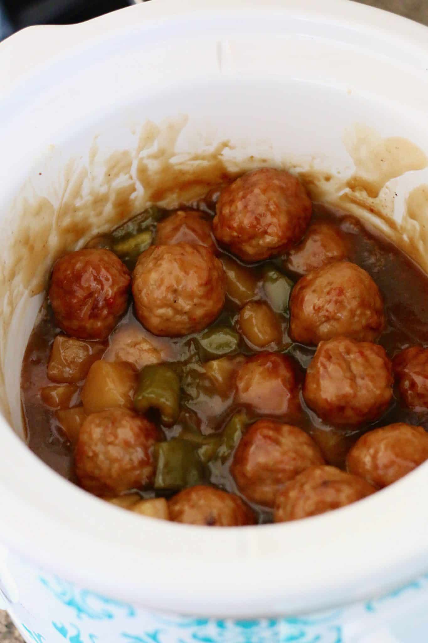 Crock Pot Sweet and Sour Meatballs shown fully cooked inside a white slow cooker. 