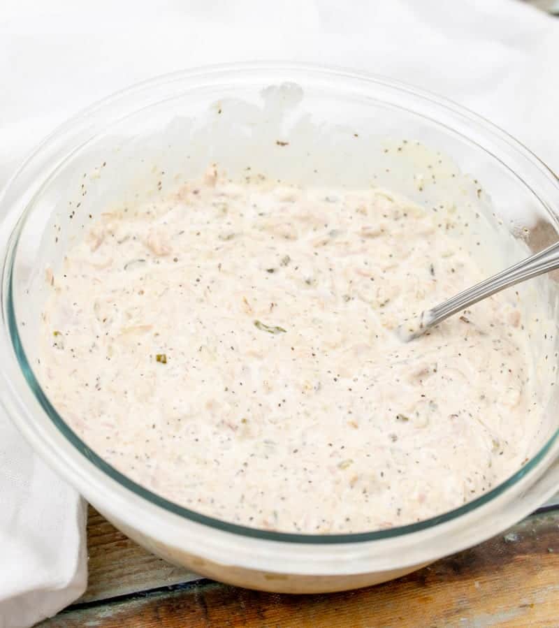 drained canned tuna added to mayonnaise mixture in a large clear bowl.