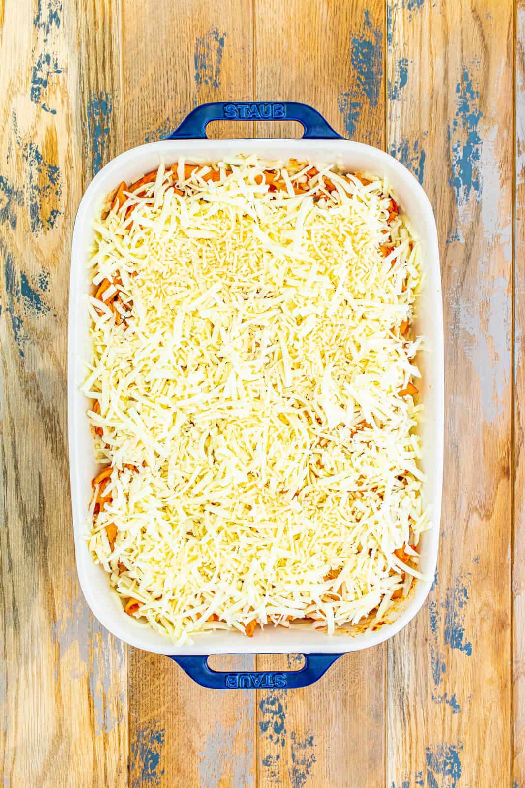 shredded cheeses spread out on top of casserole dish.