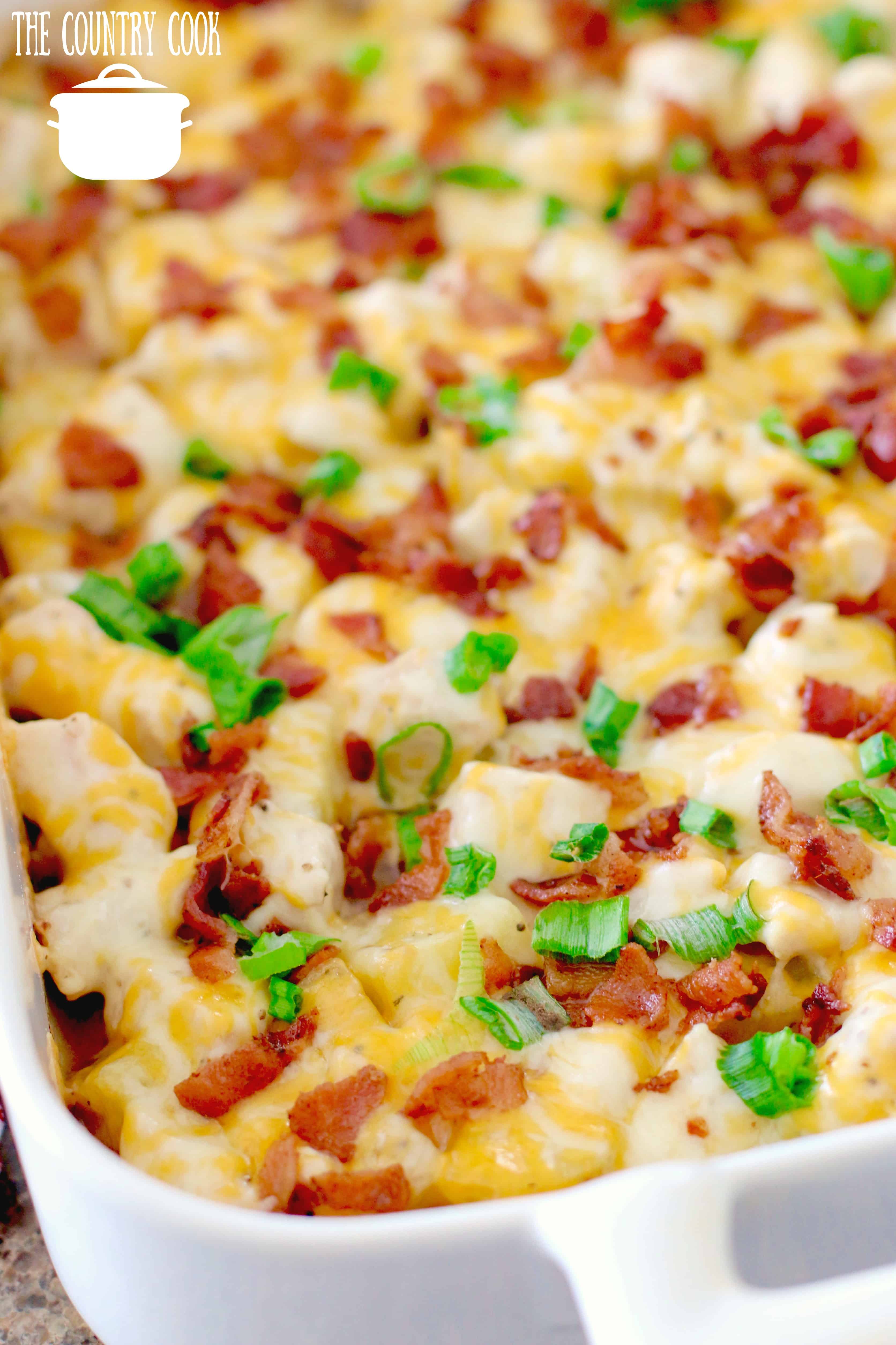 Cheddar Bacon Ranch Potato Casserole shown fully baked in a white casserole baking dish. 