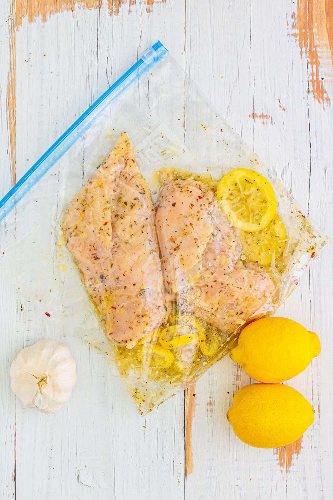 chicken breasts shown in lemon garlic marinade in a ziploc bag.