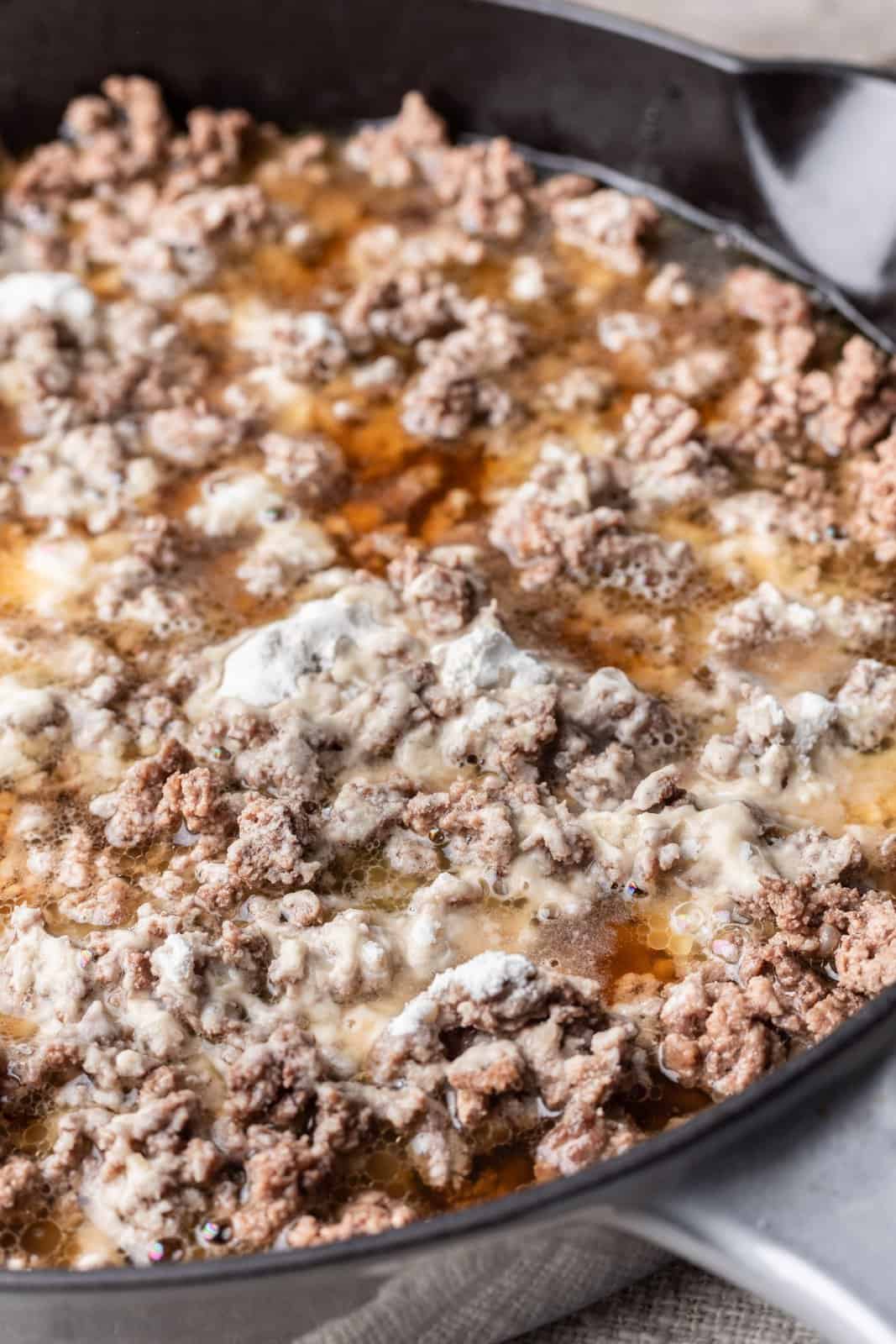 beef broth added into ground beef and flour mixture in a large skillet. 
